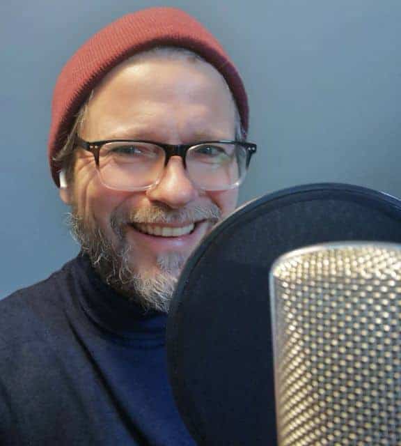 Frank Rehbein steht an einem Mikrofon und lächelt